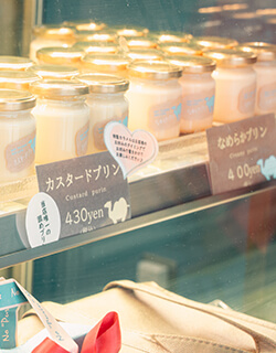 プリン専門店 Totto PURIN 砂プリン店頭 鳥取砂丘の目の前にあるプリン専門店。卵黄に高級生クリームや天然高級バニラビーンズを使用したこだわりのプリンが、定番商品から季節限定のものまで種類も豊富に楽しめます。一番人気は、クリーミーでまろやかなプリンに砂に見たてたオリジナルの自家製粉末カラメルをかけて食べる「砂プリン」。季節によって、シャインマスカットや梨などの限定フレーバーも楽しめます。鳥取県鳥取市福部町湯山