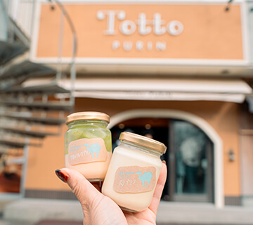 プリン専門店 Totto PURIN 砂プリン2個 大きさ 鳥取砂丘の目の前にあるプリン専門店。卵黄に高級生クリームや天然高級バニラビーンズを使用したこだわりのプリンが、定番商品から季節限定のものまで種類も豊富に楽しめます。一番人気は、クリーミーでまろやかなプリンに砂に見たてたオリジナルの自家製粉末カラメルをかけて食べる「砂プリン」。季節によって、シャインマスカットや梨などの限定フレーバーも楽しめます。鳥取県鳥取市福部町湯山