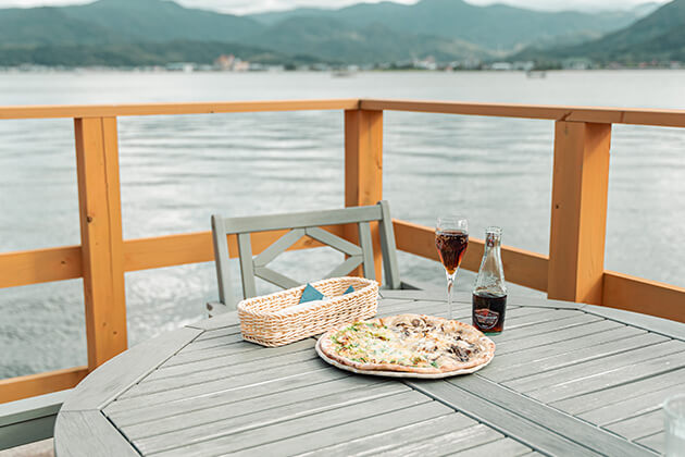 湖屋カフェ ピザ 鳥取県のほぼ真ん中に位置する湯梨浜町の東郷湖。湖畔のデッキからの美しい眺めとともに、イタリア製の石窯で焼く本格ピッツァと、湯梨浜の食材を使ったサラダ、スイーツが楽しめる絶景カフェ。敷地内にあるアウトドアの人気メーカー・スノーピーク製のモバイルハウス「住箱 JYUBAKO」には宿泊することもできます。鳥取県東伯郡湯梨浜町はわい温泉 15番地