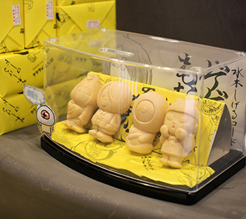 妖菓堂 鬼太郎もなか 店内鬼太郎もなかの展示 ヨウカドウキタロウ ⽔⽊しげるロードにある『妖菓堂』。円形の店内に、妖怪をモチーフにした菓子がずらりと並びます。なかでも、ゲゲゲの鬼太郎でおなじみの鬼太郎や目玉おやじ、ねこ娘、ねずみ男を形どった「ゲゲゲのもなか」が人気。手のひらサイズのもなかに特製粒あんを自分で入れて食べるスタイルで、もなかのパリパリ食感が楽しめます。⿃取県境港市本町