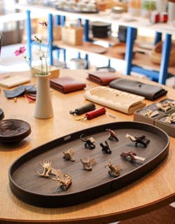 COCOROSTORE 店内の工芸品 ココロストア倉吉⼟蔵群に軒を連ね、山陰の民工芸品を販売する『COCOROSTORE 』。⿃取の豊かな自然が育んだ素材が、職人の手によって染織品や陶磁器、鍛冶、⽊竹工、和紙など、さまざまな生活道具に変わり、使う人の生活をより豊かにする。そんな作品を中心に取り扱っています。心に響くお気に入りの一点が見つかるはず。⿃取県倉吉市魚町