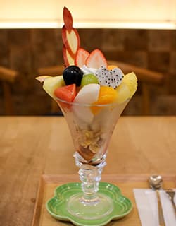 フルーツカフェサエキ パフェと店内の様子『米子市美術館』併設の『フルーツカフェサエキ』。季節のフルーツがたっぷり楽しめるモーニングやブランチのセットメニューのほかに、フルーツサンドやパフェなどのスイーツや100%フレッシュジュースなどが味わえます。向かいには『米子市立図書館』もあり、芸術や文化にふれながらフルーツをぜいたくに楽しめるカフェです。⿃取県米子市中町